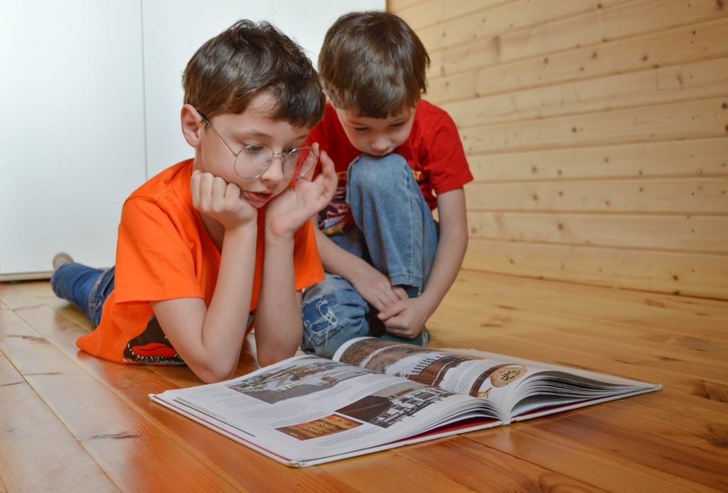 Duas crianças olham para um livro e apreciam uma boa leitura.