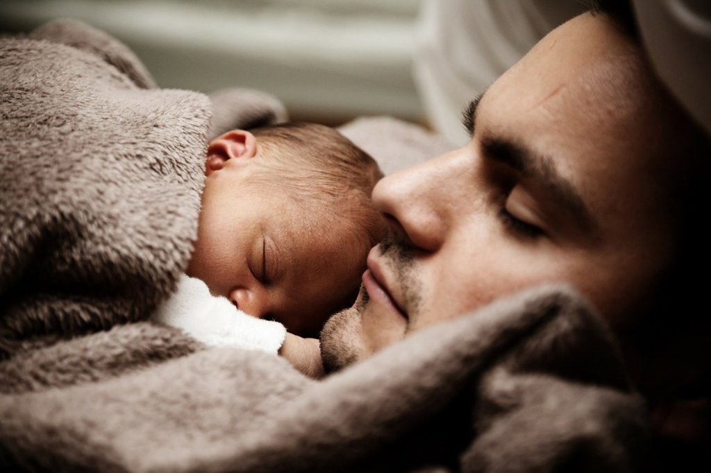 Na foto, bebê dorme próximo ao rosto do seu pai.