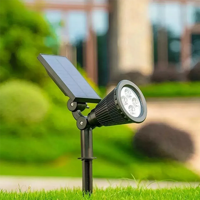 Espeto de LED instalado no jardim, fincado no chão em meio ao gramado. Ele possui um painel solar para alimentação de energia.